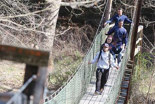 STudents cross suspension bridge during an orientation day hike